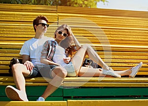 Young modern stylish hipsters couple rest in bench city park