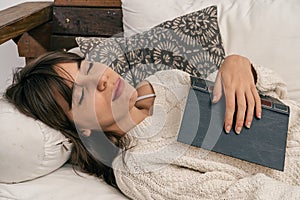 Young modern woman falls asleep while reading a book lying on the sofa. Tiredness, rest concept