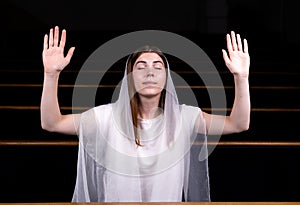 A young modest girl with a handkerchief on her head is sitting in church and praying. The concept of religion, prayer, worship