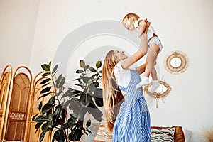 Young mom or babysitter playing with little child at home