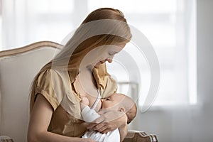 Young mom breastfeed little newborn child at home