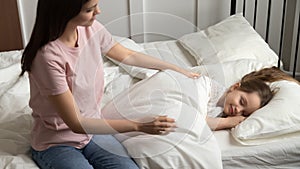 Young mom caress little daughter put her to sleep photo