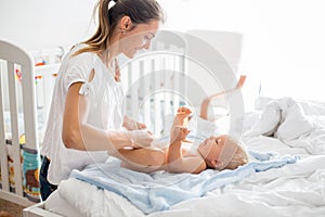 Young mom, changing baby diaper after bath