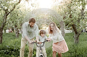 Young mom and dad teach their son to ride a bike