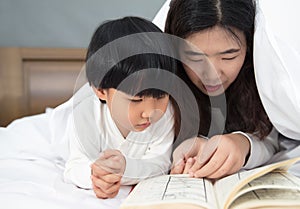 Young mom and daughter telling storybook in bed