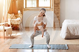 Young mom exercising with her baby boy at home