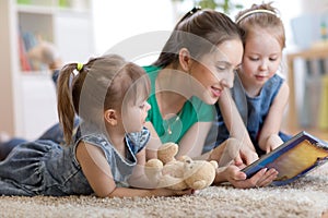Young mom and her children lying on the floor and reading book