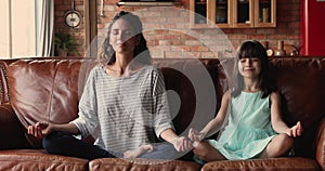 Young mom her daughter do meditation practice at home