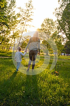 Young mom and her small daughter are walking holding hands