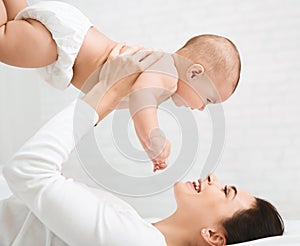 Young mom holding her happy baby in air