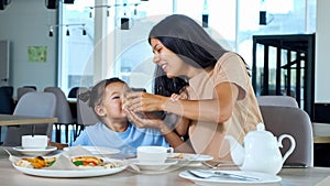 Young mom holds pizza slice and child girl eats playing