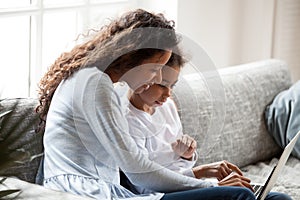 Young mom and little daughter using laptop together