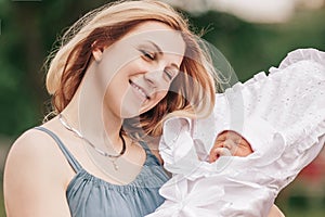 Young mom with newborn baby on blurred nature background.