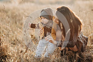 Young mom playing with her little baby boy son in autumn