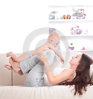 Young mom playing with a pretty baby on the couch