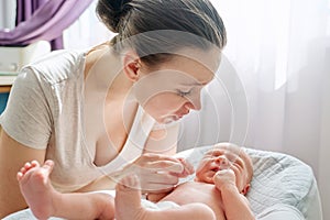 Young mom talking to crying newborn baby son