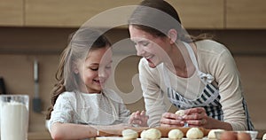 Young mom teach her little daughter to prepare pastries