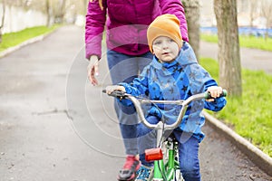 Young mom teaching son to ride bike first time in park