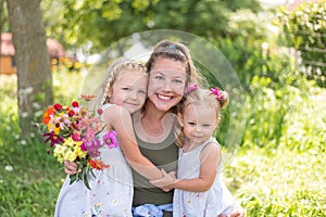 Young mom with two little girls and a bouquet of summer flowers