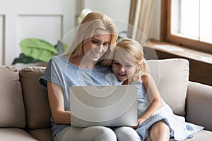 Young mom watch video on laptop with little daughter
