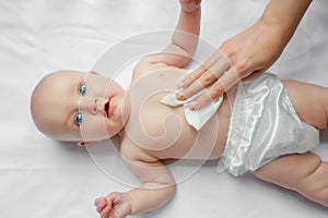 Young mom wiping the baby skin body and face with wet wipes carefully on white background. concept cleaning wipe, pure, clean