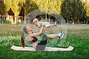Young mom workout on nature grass lawn with baby