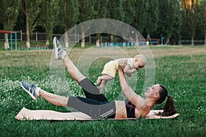 Young mom workout on nature grass lawn with baby