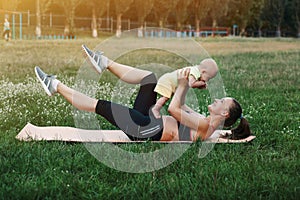 Young mom workout on nature grass lawn with baby