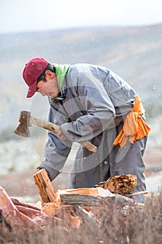 Young Mongolian man axing firewood.