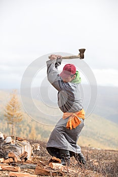 Young Mongolian man axing firewood.