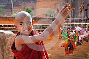 A young monk playing with puppets in Bagan, Myanmar