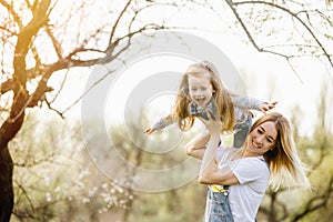 Young mother with adorable daughter in park with blossom tree