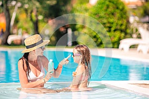 Young mother applying sun cream to daughter nose