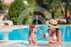 Young mother applying sun cream to daughter nose on the beach.