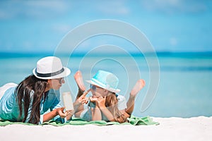 Young mother applying sun cream to daughter nose on the beach.