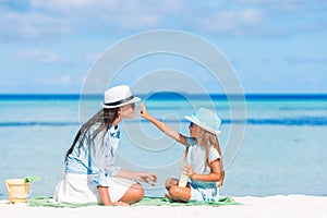 Young mother applying sun cream to daughter nose on the beach.