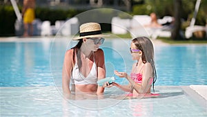 Young mother applying sun cream to daughter nose on the beach.