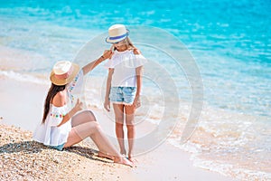 Young mother applying sun cream to daughter nose on the beach. Sun protection