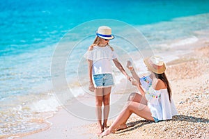 Young mother applying sun cream to daughter nose on the beach. Sun protection