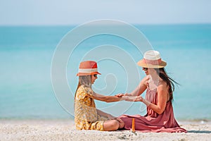 Young mother applying sun cream to daughter nose on the beach. Sun protection