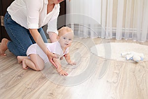Young mother and baby daughter, son are having fun at home. Beautiful mom throws her adorable newborn infant up and