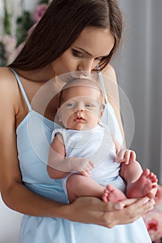 Young mother with baby in hands at home in the bedroom