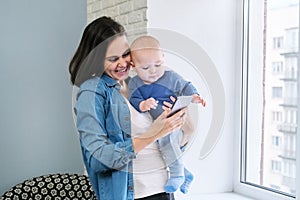 Young mother and baby are looking at smartphone screen, video call