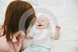 Young mother and baby lying on the bed at home