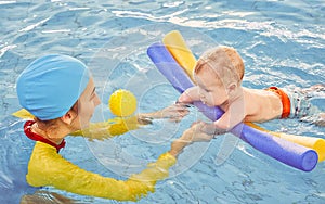 Young mother and baby son are in pool teaches swim