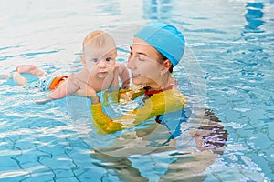 Young mother and baby son are in pool teaches swim