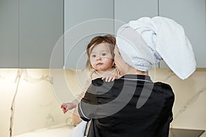 Young mother with baby in towels after shower in bathroom. Concept of hygiene and cleanliness