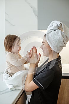 Young mother with baby in towels after shower in bathroom. Concept of hygiene and cleanliness