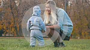 Young mother with a baby walking in the autumn park. Mother tickles her baby