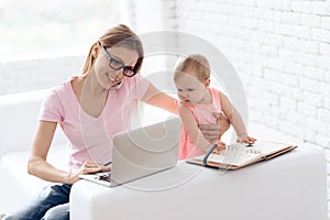 Young mother with baby working and using laptop.